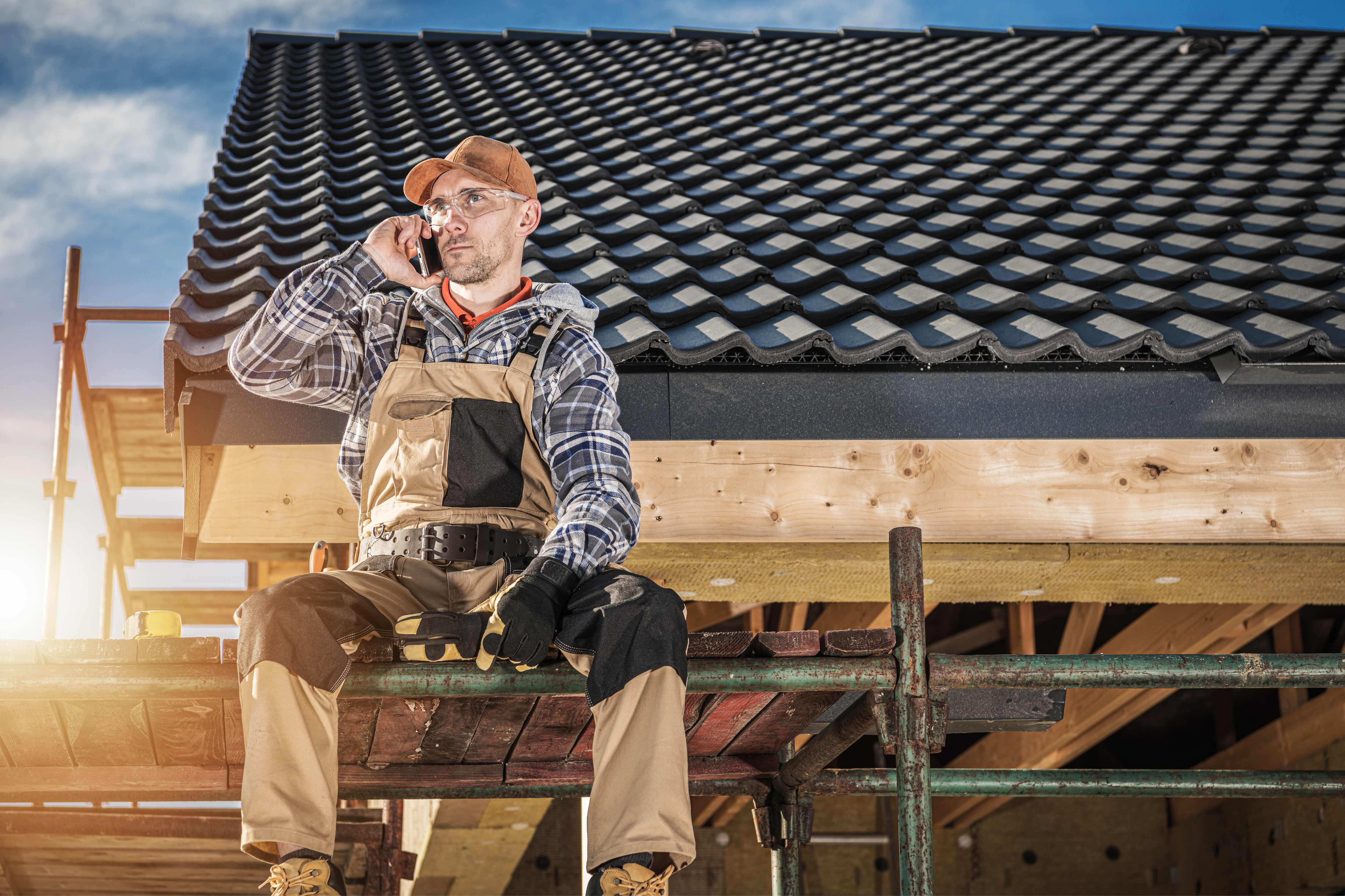 Construction worker on phone call while on a roof